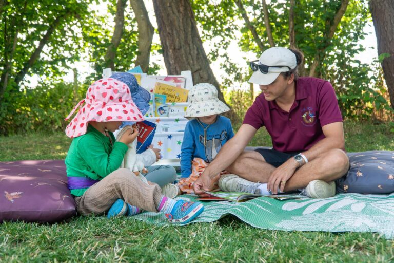 Children listening to stories being read to them whilst outdoors at the Pheasant Nest